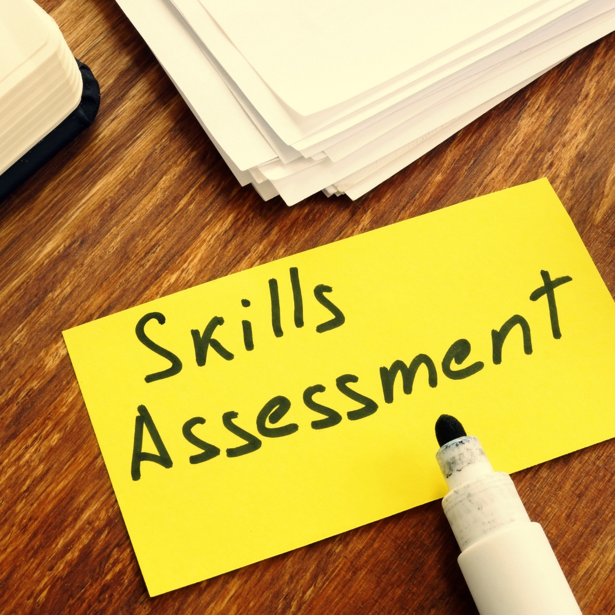 An organized desk with a yellow paper written on it 'Skills Assessment' with a black marker for blog Qualifications for Migrating to Australia